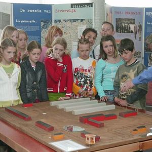 Jan van der Linden geeft uitleg bij de maquette van het Kamp Zöschen aan een groep scholieren